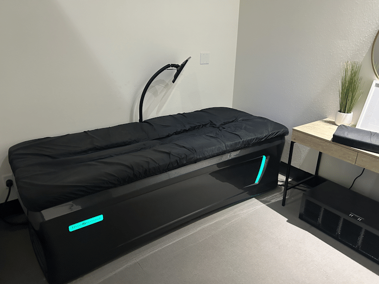 Side view of a black hydro massage therapy bed.
